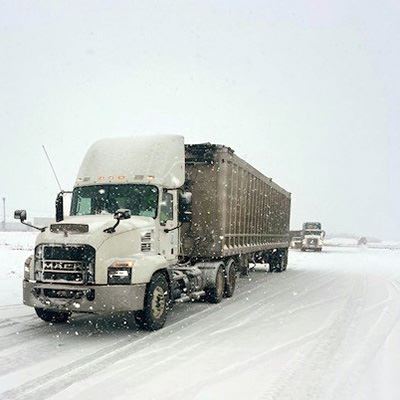 An 18-wheel truck drives through a snowstorm